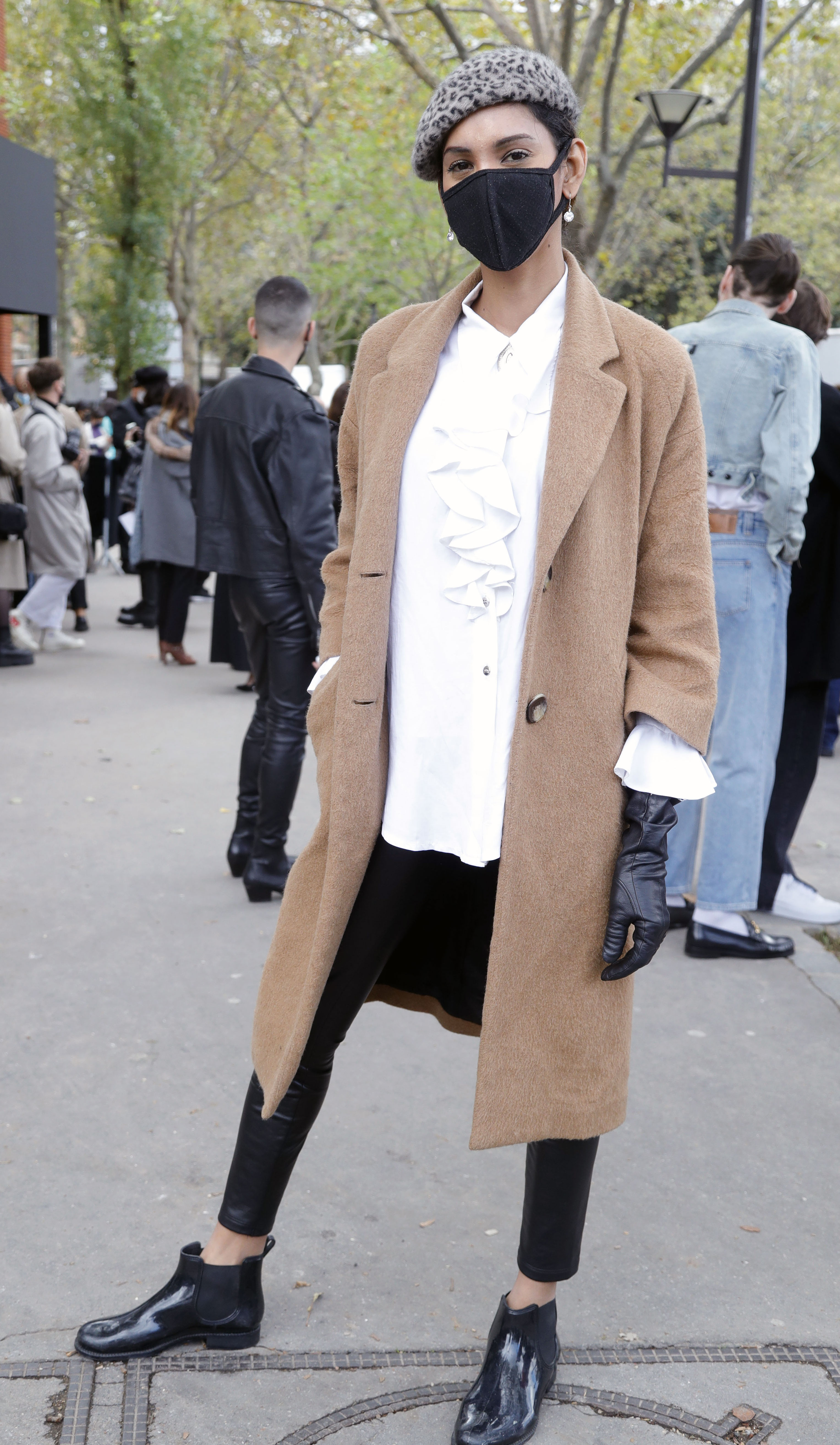 Paris Fashion Week Street Style: woman in a beret, face mask, a beige coat, and black accessories.