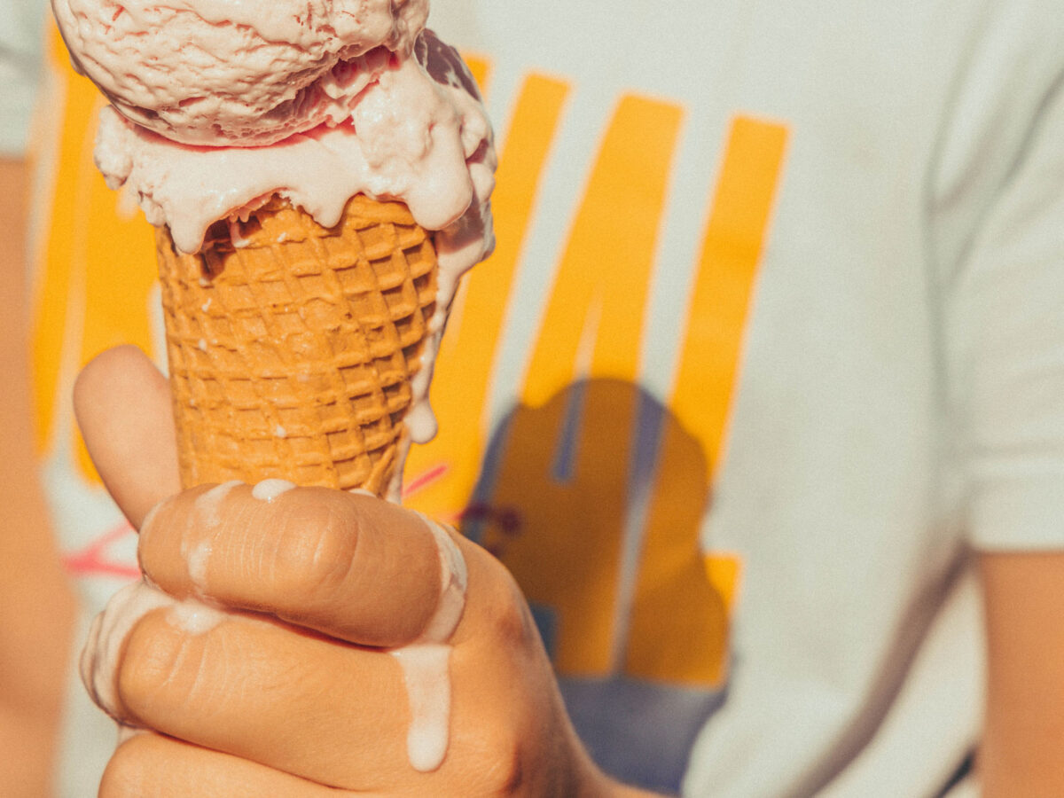 Kid holding ice cream cone melting in hot summer.
