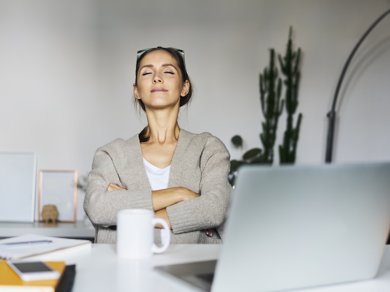 Young woman at home with laptop on desk having a break