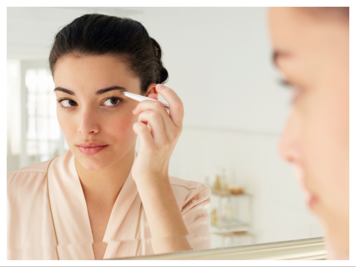 woman-in-a-mirror-brushing-her-eyebrow