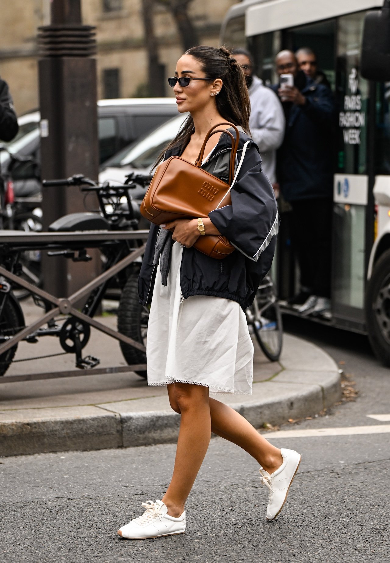 Tamara Kalinic is seen wearing a gray Miu Miu top, black Miu Miu jacket, white skirt, white sneakers and brown Miu Miu bag and black sunglasses outside the Miu Miu show during the Womenswear Fall/Winter 2025/2026