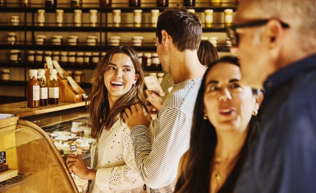 Medium shot of group of happy customers shopping at crowded local artisanal food shop