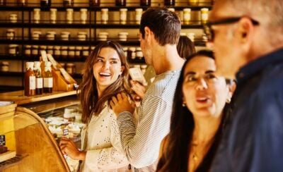 Medium shot of group of happy customers shopping at crowded local artisanal food shop