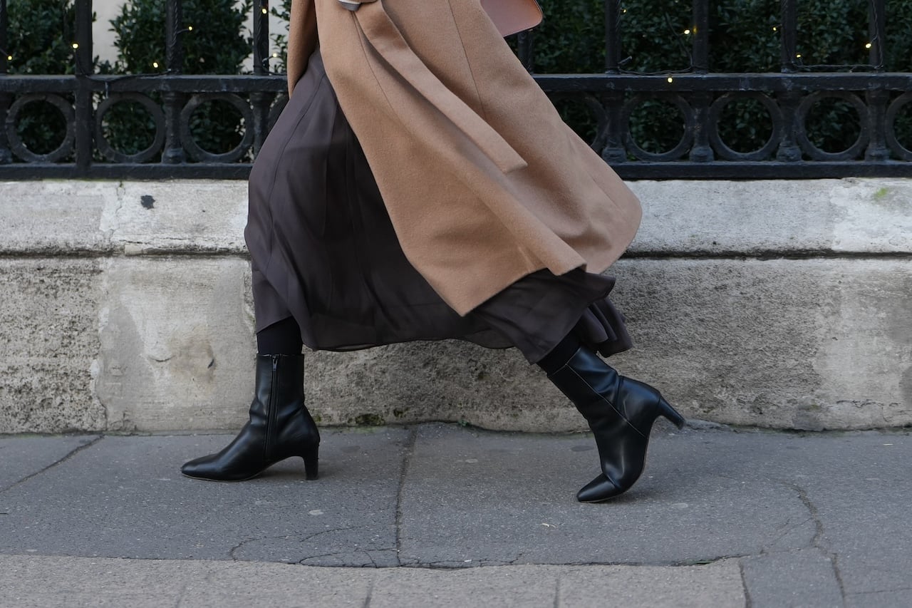 PARIS, FRANCE - DECEMBER 18: A passerby wears a brown long wool winter coat, a long dark purple sheer dress, high heel black leather pointed boots, during a street style fashion photo session, on December 18, 2025 in Paris, France. (Photo by Edward Berthelot/Getty Images)