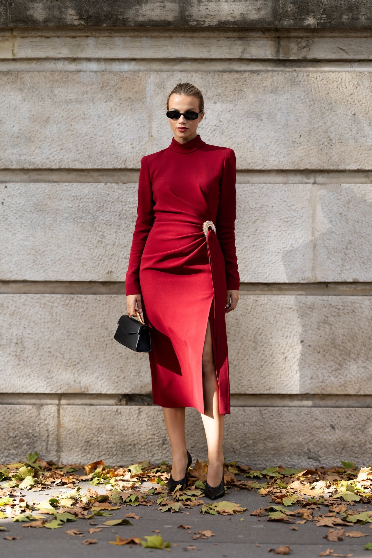 PARIS, FRANCE - OCTOBER 04: Simona Jakstaite wears black leather pumps, a black leather bag, black sunglasses and a red turtle neck long sleeved midi dress with a gold pin outside Elie Saab show during the Womenswear Spring Summer 2026 as part of Paris Fashion Week on October 04, 2025 in Paris, France. (Photo by Valentina Frugiuele/Getty Images)