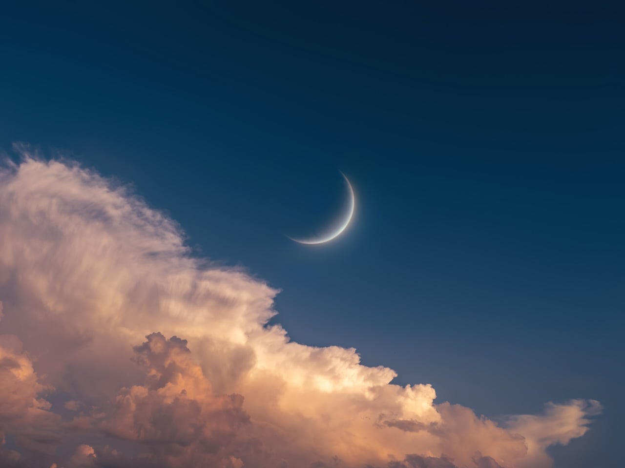 Young Moon in the sky at sunset. Big Moon above the clouds. Celestial landscape (Photo via Getty Images).