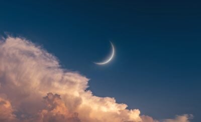 Young Moon in the sky at sunset. Big Moon above the clouds. Celestial landscape (Photo via Getty Images).