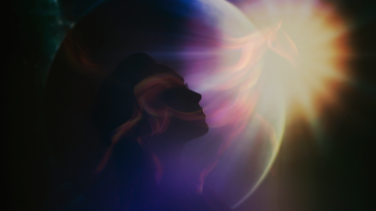 A silhouette of a woman’s profile set against a glowing planet and a radiant sunburst. This ethereal composition symbolizes inner strength, cosmic connection, and the limitless power of the human soul.