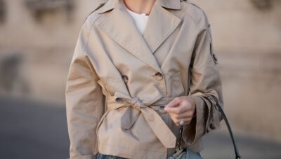 Cropped Trench Spring 2026; MUNICH, GERMANY - JULY 18: Marlies Pia Pfeifhofer is seen wearing a cropped beige double-breasted trench jacket with waist belt, wide lapels, raglan sleeves and shoulder epaulettes from Pennyblack; a cream white sleeveless textured linen top with round neckline and asymmetric front panel from Sézane; light blue washed ultra wide leg Paloma jeans in structured denim with high waist and long flared silhouette from Citizens of Humanity; beige Dolly Verona raffia platform sandals with thick sole from Larroudé; a pastel matcha green Fendi Mamma Baguette Small shoulder bag in soft nappa leather with top handle and golden metal hardware; a surigao pearl necklace with red Japanese glass beads and a freshwater baroque pearl from Les Beads Studio; a diamond ring; her blonde hair is worn in a bob on July 18, 2025 in Munich, Germany. (Photo by Moritz Scholz/Getty Images)