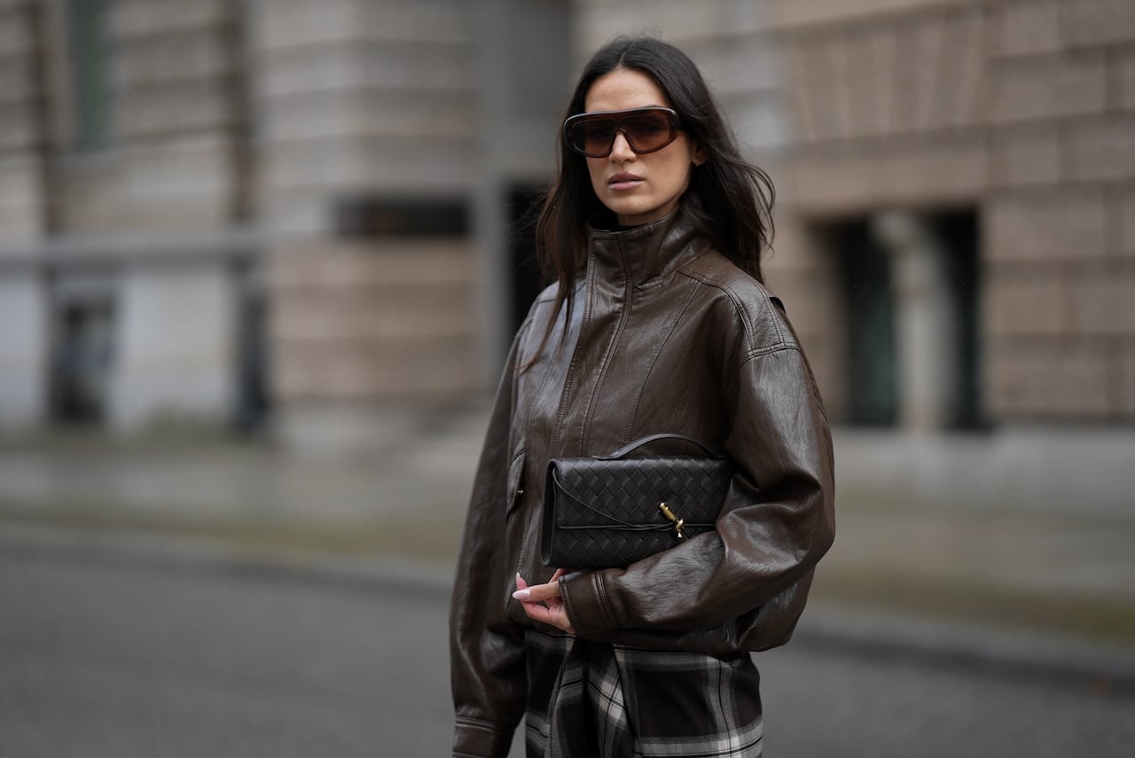BERLIN, GERMANY - OCTOBER 22: Amanda Azoitei is seen wearing a dark brown oversized leather bomber jacket with a high collar and contrast stitching by The Frankie Shop;a dark brown woven leather clutch with a gold metal clasp by Bottega Veneta; oversized rectangular sunglasses with a gradient tint and brown frame by Gigi Studios; her long dark brown hair is worn straight and loose on October 22, 2025 in Berlin, Germany. (Photo by Moritz Scholz/Getty Images)