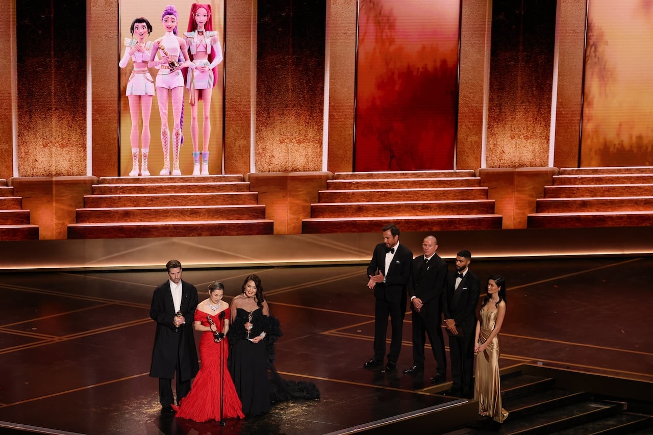 US director Chris Appelhans (L), South Korean-Canadian storyboard artist and writer Maggie Kang and producer Michelle Wong speak onstage after accepting the Oscar for Best Animated Feature Film "KPop Demon Hunters" during the 98th Annual Academy Awards at the Dolby Theatre in Hollywood, California on March 15, 2026. (Photo by Patrick T. Fallon / AFP)