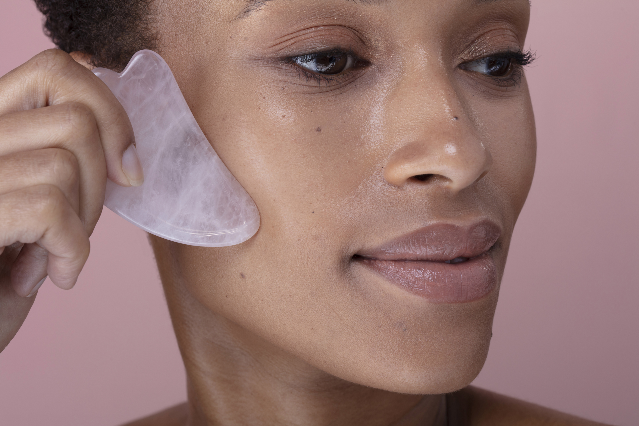 Close-up of woman massaging face with rose quartz guasha